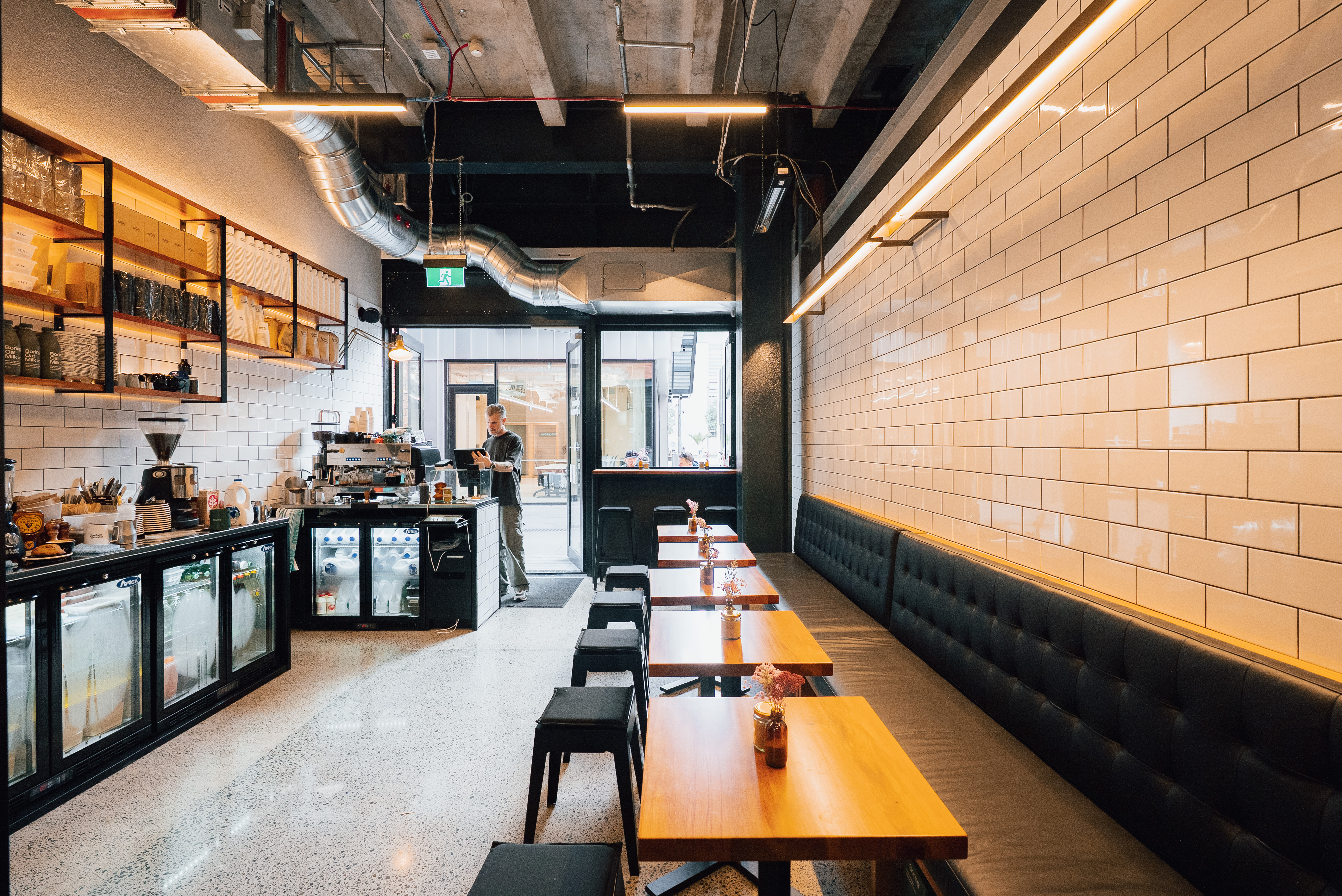 Inside Goodness Gracious Wynyard Quarter — banquette seating, white-tiled wall, espresso bar